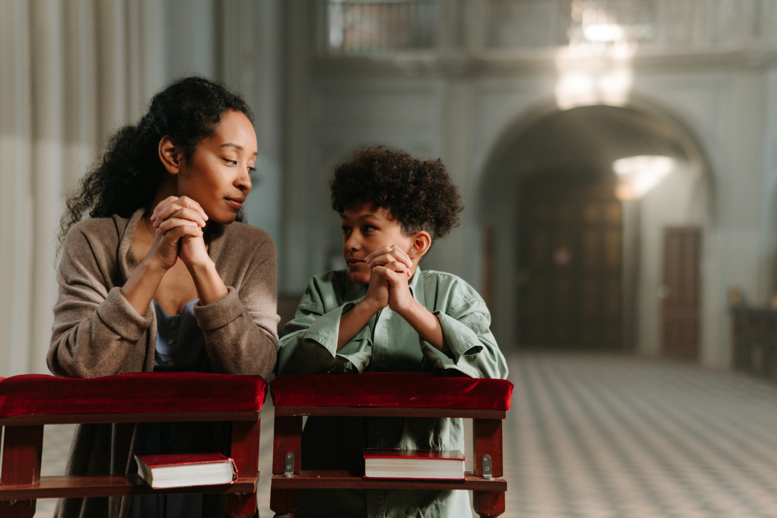 Mother and son praying at Catholic mass, featured in Apostle Times.
