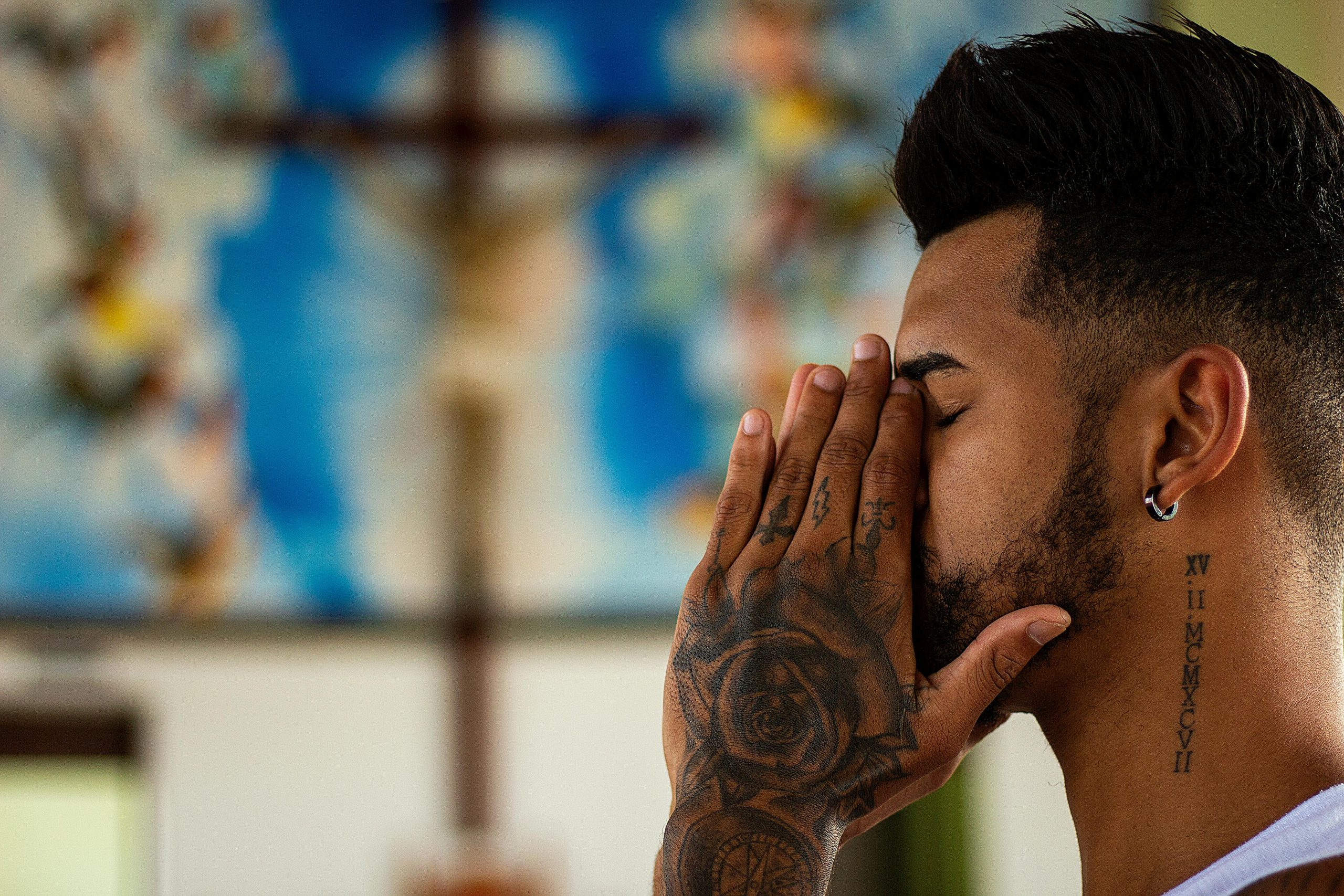 Catholic man with tattoos praying inside a church, featured in Apostle Times Catholic news blog.